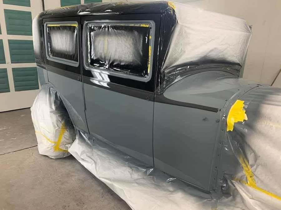 The same sedan in the paint booth wearing fresh two-tone slate and black paint